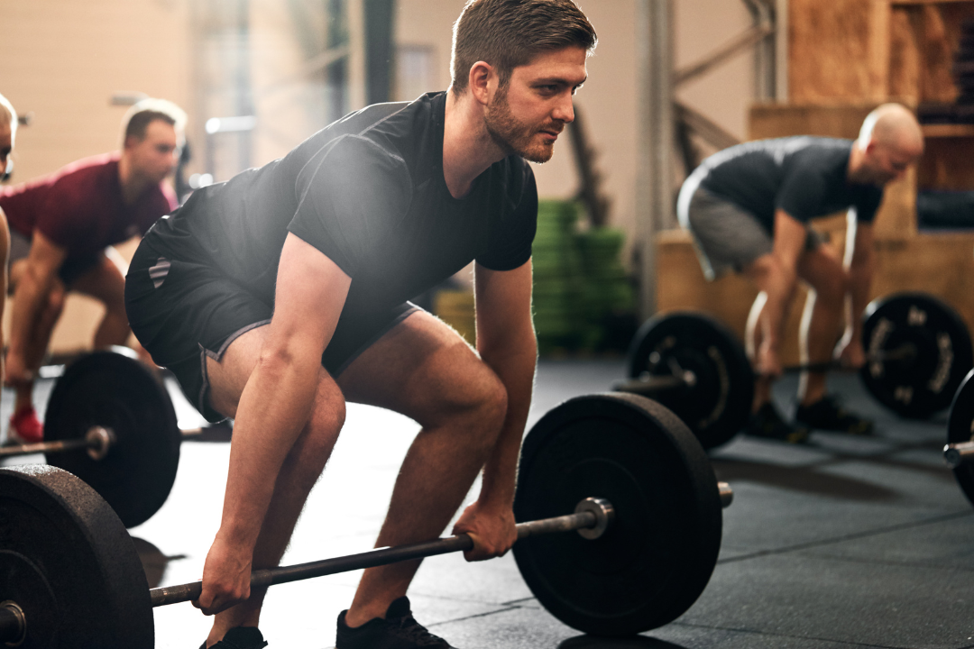 Ragazzi in palestra che sollevano pesi con il bilanciere 